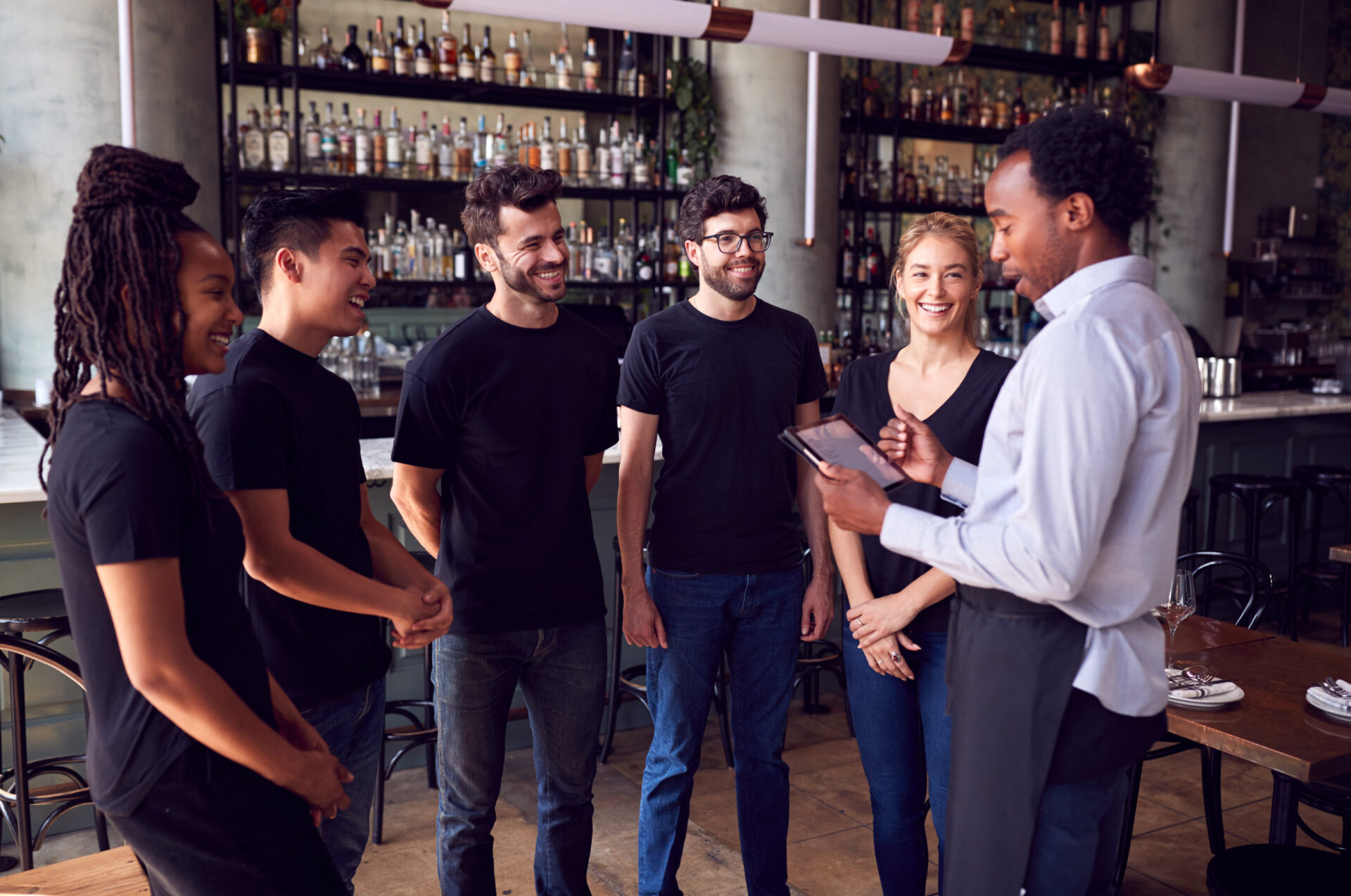 Male Restaurant Manager With Digital Tablet Giving Team Talk To Waiting Staff