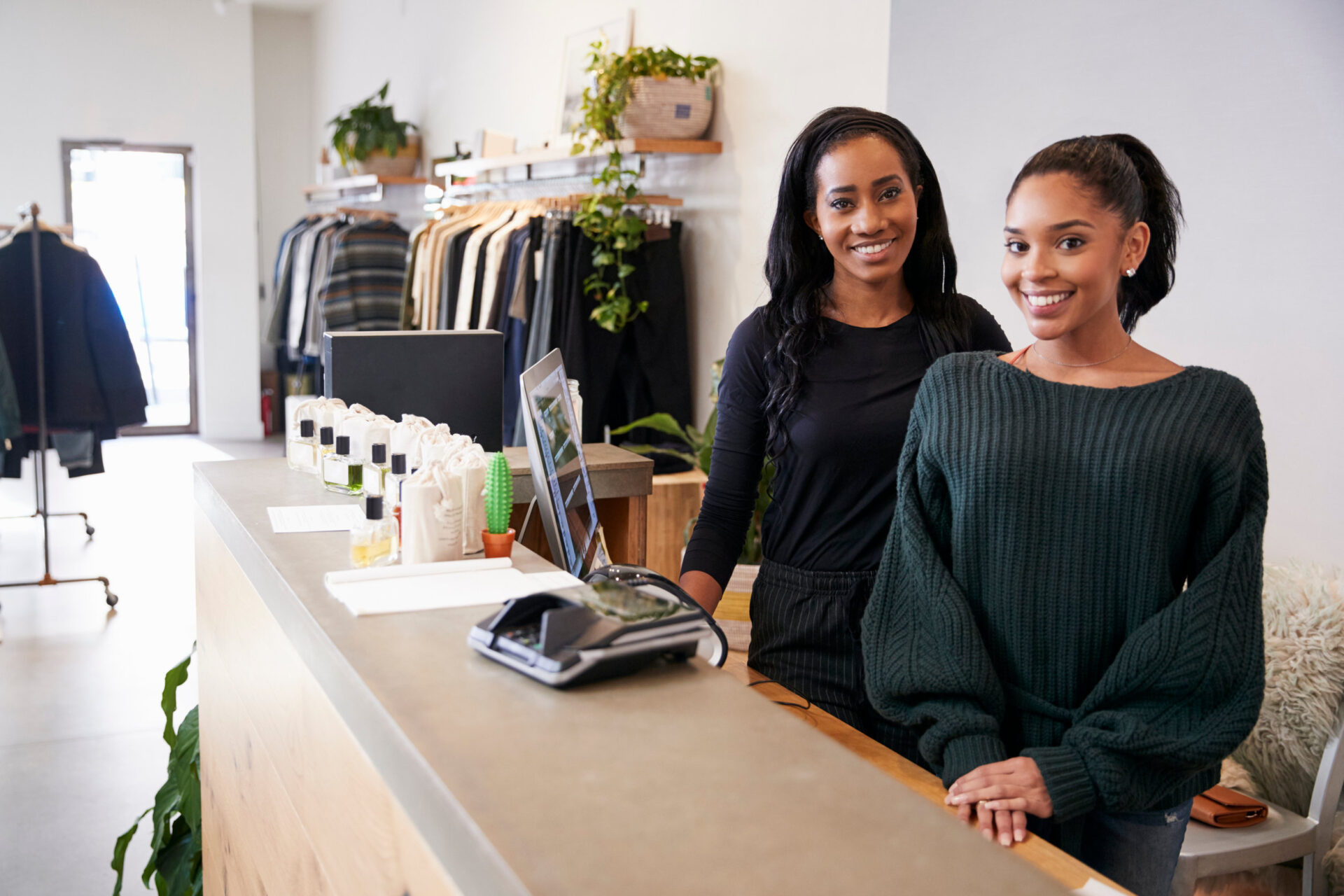 Two women smiling behind the counter in clothing store